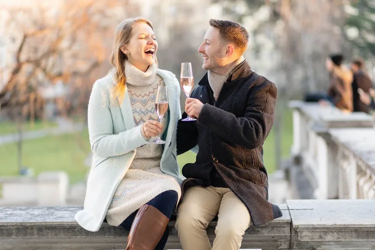 Newly engaged couple laughing and toasting with champagne in the Burggarten